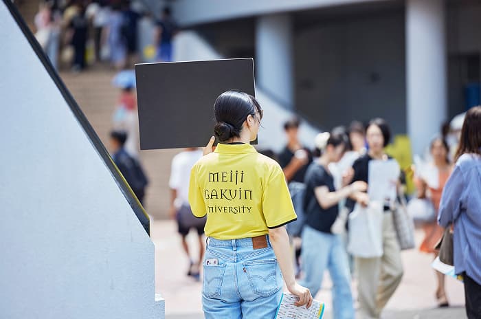 案内板を持つスタッフ学生の後ろ姿